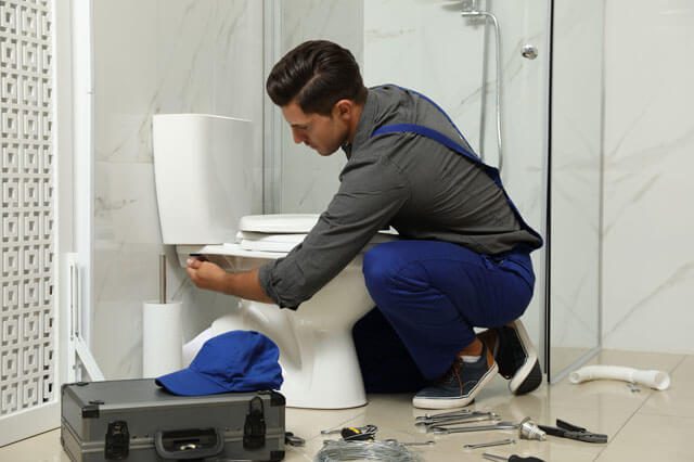  a plumbing technician working on a toilet bowl 