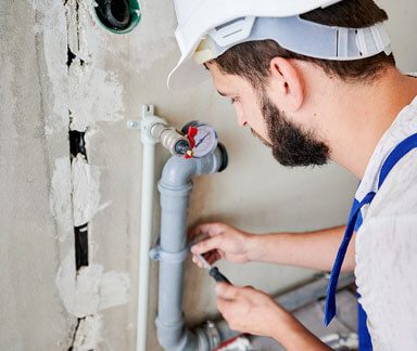  a plumber fixing a pipe on the wall 