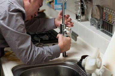  a plumber installing a kitchen faucet 