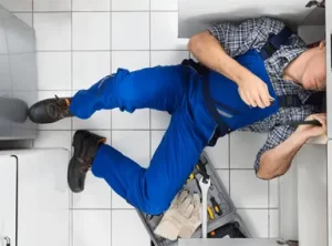a professional plumber repairing drain lines under the kitchen sink